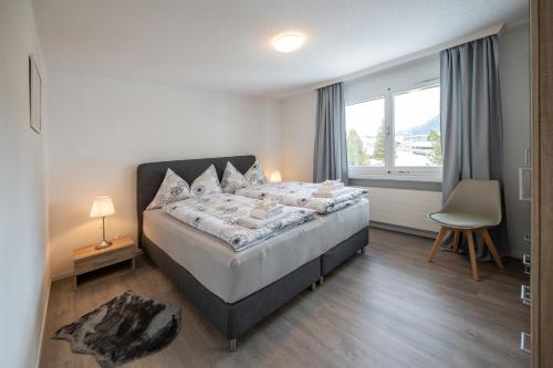 a bedroom with a large bed and a window at Agrimonia - möbilierte Ferienwohnung mit Balkon in Davos