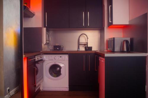 a kitchen with black cabinets and a washing machine at Plus haut jacuzzi d’Europe, 40e étage in Puteaux