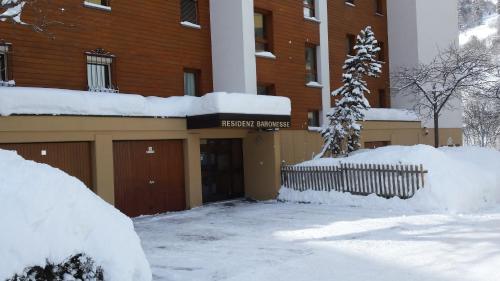 a building with snow on the ground in front of it at Baron / Baronesse Apartments in Leukerbad
