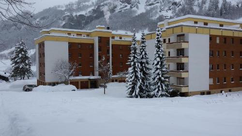 a large building in the snow with snow covered trees at Baron / Baronesse Apartments in Leukerbad