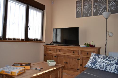 a living room with a tv on a wooden dresser at Casa Rural El Dolmen in Bernúy-Salinero