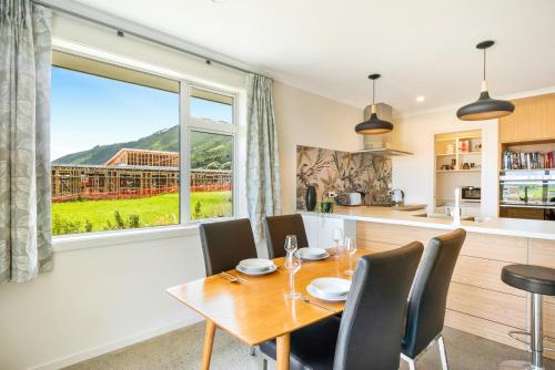 a dining room with a table and chairs and a large window at Matenga Townhouse - Waikanae Holiday Home in Waikanae