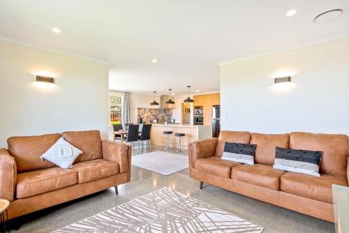 a living room with two brown leather couches at Matenga Townhouse - Waikanae Holiday Home in Waikanae