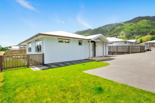 a white house with a fence and a yard at Matenga Townhouse - Waikanae Holiday Home in Waikanae