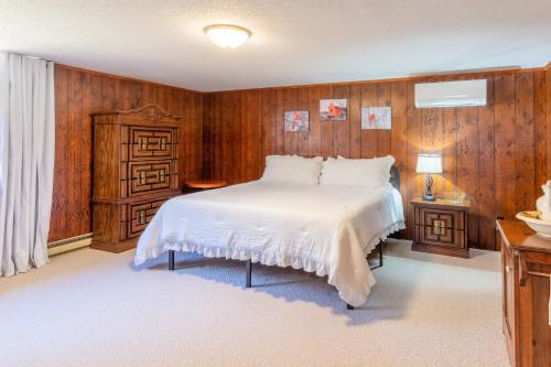 1 dormitorio con cama blanca y paredes de madera en Cardinal's Nest, en Cullowhee