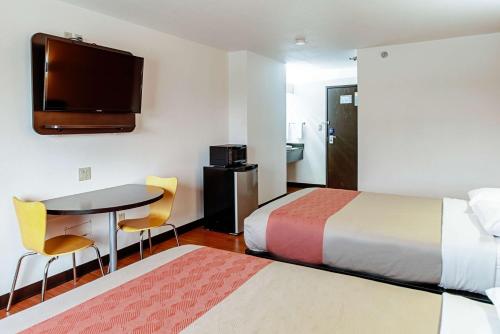 Cette chambre comprend 2 lits, une table et une télévision. dans l'établissement Motel 6-Lebanon, IN, à Lebanon
