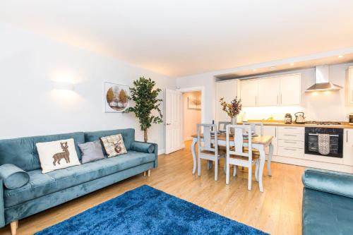 a living room with a blue couch and a kitchen at Luxury Modern 3 Bedroom Apartment in City Centre in Edinburgh