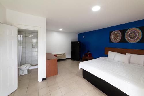 ein Schlafzimmer mit einem Bett und einer blauen Wand in der Unterkunft American Inn in Baton Rouge