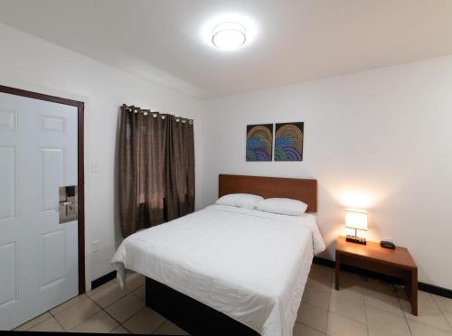 ein Schlafzimmer mit einem Bett und einem Tisch mit einer Lampe in der Unterkunft American Inn in Baton Rouge