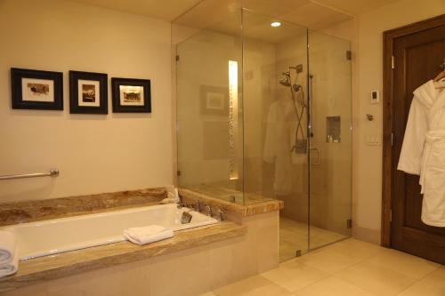 帕克城的住宿－Deluxe Two Queen Room with Fireplace Hotel Room，带浴缸和玻璃淋浴间的浴室。