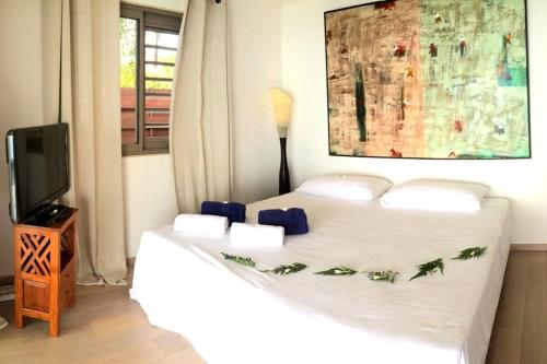 a bedroom with a large white bed and a tv at TAHITI - La Villa Vahineria Dream 5 pax in Punaauia