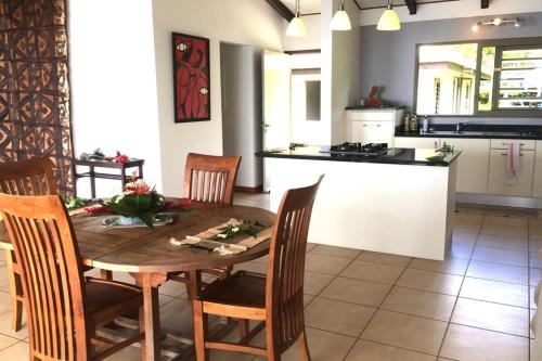 eine Küche und ein Esszimmer mit einem Holztisch und Stühlen in der Unterkunft TAHITI - La Villa Vahineria Dream 5 pax in Punaauia