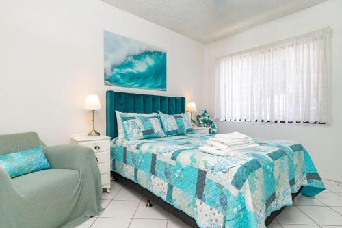 a bedroom with a bed and a chair at Carinya Gardens 15 in Forster
