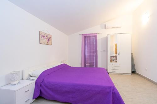 a white bedroom with a purple bed and a mirror at Apartments by the sea Mandre, Pag - 3084 in Kolan