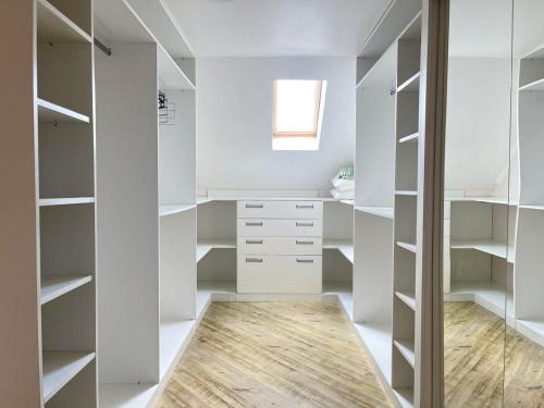 una cabina armadio con armadi bianchi e una finestra di Apartamentos Dioserra CENTRO by Achei Gramado a Gramado