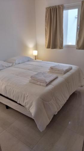 a bedroom with a large white bed with a window at Bahia sin fondo in Puerto Madryn
