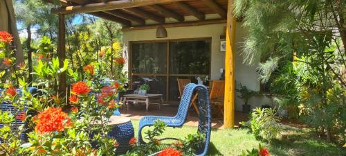 a garden with a blue chair in the yard at Bangalô Tavarua Itacimirim Pé na areia in Itacimirim