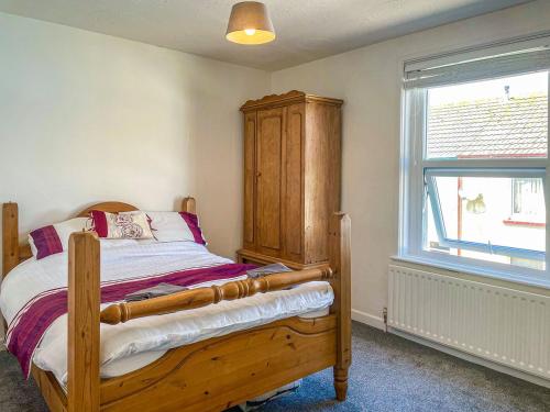 een slaapkamer met een houten bed en een raam bij Gwens House in Melcombe Regis