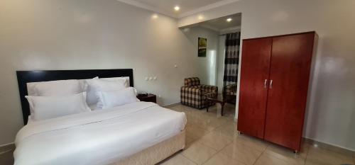 1 dormitorio con 1 cama blanca grande y armario de madera en Traveller's StaY en Kigali