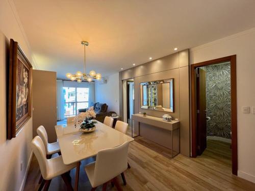 a dining room with a table and chairs and a mirror at Apartamentos Rossa Residenzialle CENTRO by Achei Gramado in Canela