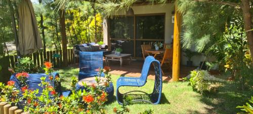 a garden with blue chairs and flowers in the yard at Bangalô Tavarua Itacimirim Pé na areia in Itacimirim