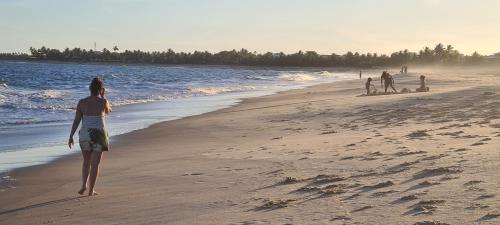 a person walking on the beach at Bangalô Tavarua Itacimirim Pé na areia in Itacimirim