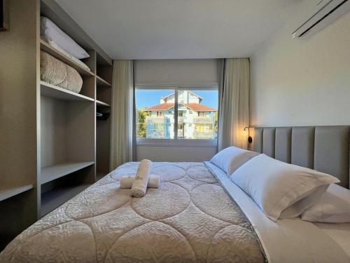 a bedroom with a large bed with a window at Apartamentos Rossa Residenzialle CENTRO by Achei Gramado in Canela