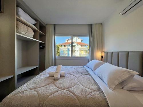 1 dormitorio con 1 cama grande y ventana en Apartamentos Rossa Residenzialle CENTRO by Achei Gramado, en Canela
