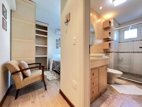 y baño con lavabo, aseo y silla. en Apartamentos Residencial Vale Enotria by Achei Gramado, en Gramado