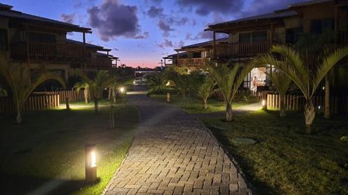 a walkway in a resort with a candle in the grass at Bangalô Tavarua Itacimirim Pé na areia in Itacimirim
