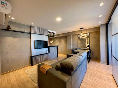 sala de estar con sofá grande y TV en Apartamentos Vita Boulevard CENTRO by Achei Gramado, en Gramado