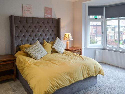 ein Schlafzimmer mit einem großen Bett mit gelber Bettwäsche und Kissen in der Unterkunft Two The Manor Born in Tynemouth