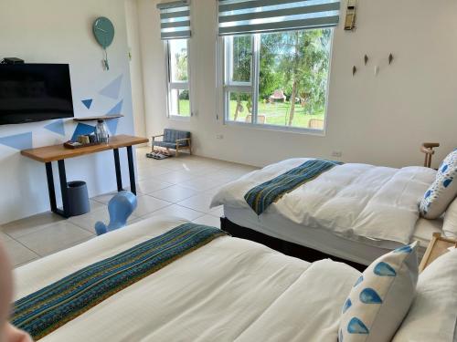 a room with two beds and a tv and a window at Mei Jung B&B in Zhixue