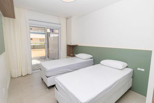 2 camas en una habitación con ventana en Caraíbas 01 - Excelente apartamento garden 2 suítes - À poucos metros da praia, en Bombinhas