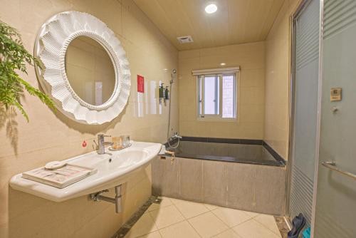 a bathroom with a sink and a shower and a mirror at Ashare Hotel in Jiaoxi