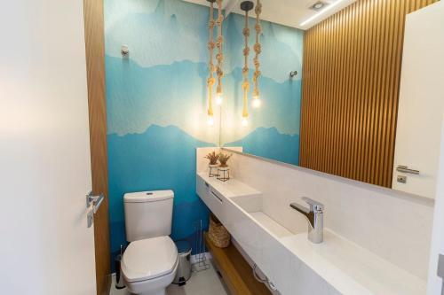 y baño con aseo, lavabo y espejo. en Puntarenas 202 - Excelente apartamento 2 suítes - Finamente mobiliado e decorado - À poucos metros da praia, en Bombinhas
