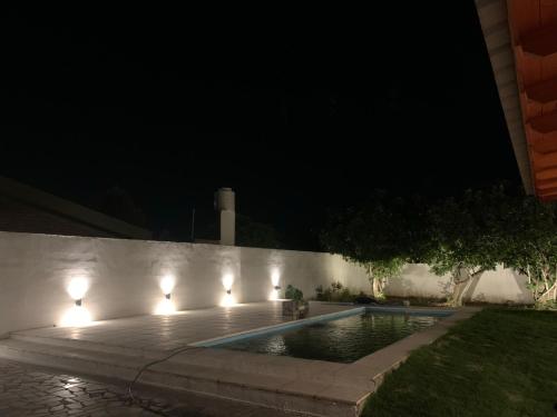 - une piscine avec des lumières sur un mur la nuit dans l'établissement Zama - Complejo de cabañas, à Villa de Soto