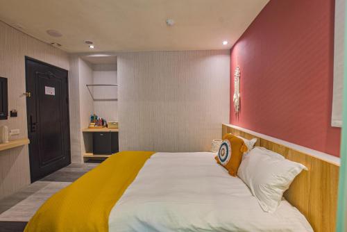 a bedroom with a large bed with a red wall at Ashare Hotel in Jiaoxi
