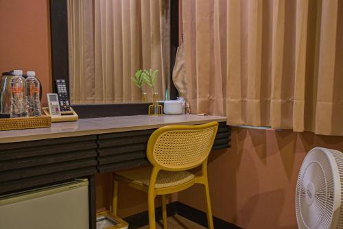 a yellow chair sitting at a desk in a room at Ashare Hotel in Jiaoxi
