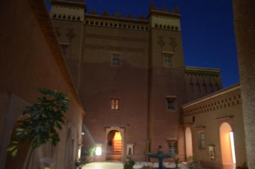 a large building with a clock tower at night at Kasbah Ait Kassi in Boumalne