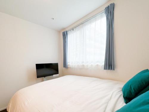 a bedroom with a white bed and a television at MAT OSHIAGE Ⅱ in Tokyo