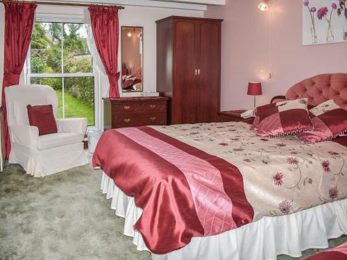 een slaapkamer met een bed, een stoel en een raam bij Anneth Lowen in Perranwell