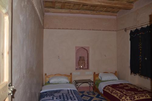 a bedroom with two beds and a window at Kasbah Ait Kassi in Boumalne