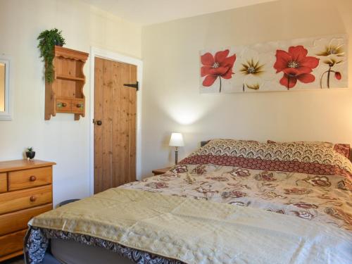 a bedroom with a bed with flowers on the wall at Sea Breeze in Mossbay