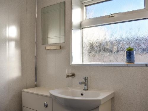 baño con lavabo y ventana en Sea Breeze, en Mossbay