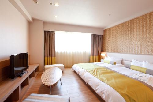 um quarto de hotel com uma cama grande e uma televisão em Kusatsu Estopia Hotel em Kusatsu