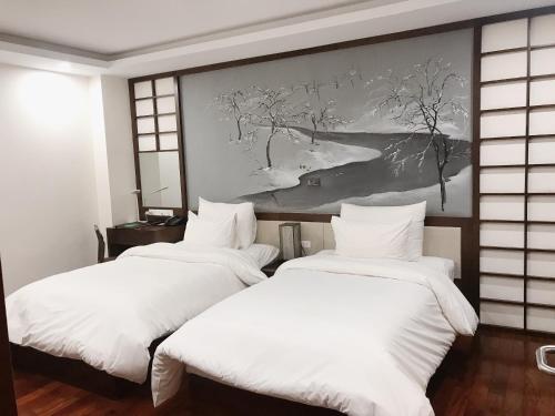 2 Betten in einem Zimmer mit Wandgemälde in der Unterkunft Brandi Fuji Hotel in Hanoi