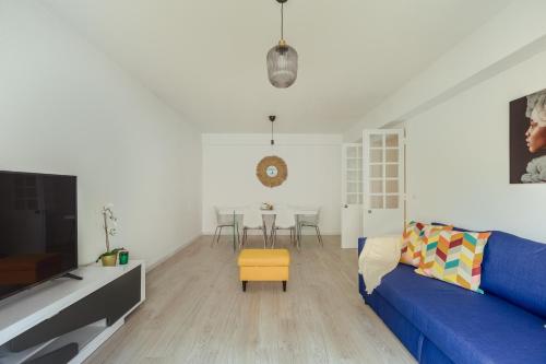 uma sala de estar com um sofá azul e um banco amarelo em Elegant 3 bedroom apt - City centre - garage - metro em Lisboa