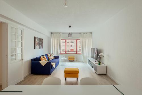 a living room with a blue couch and a window at Elegant 3 bedroom apt - City centre - garage - metro in Lisbon