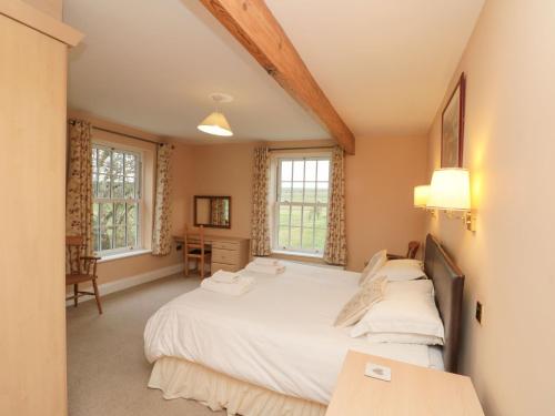 um quarto com uma cama grande e 2 janelas em Foreman's House em Rudston